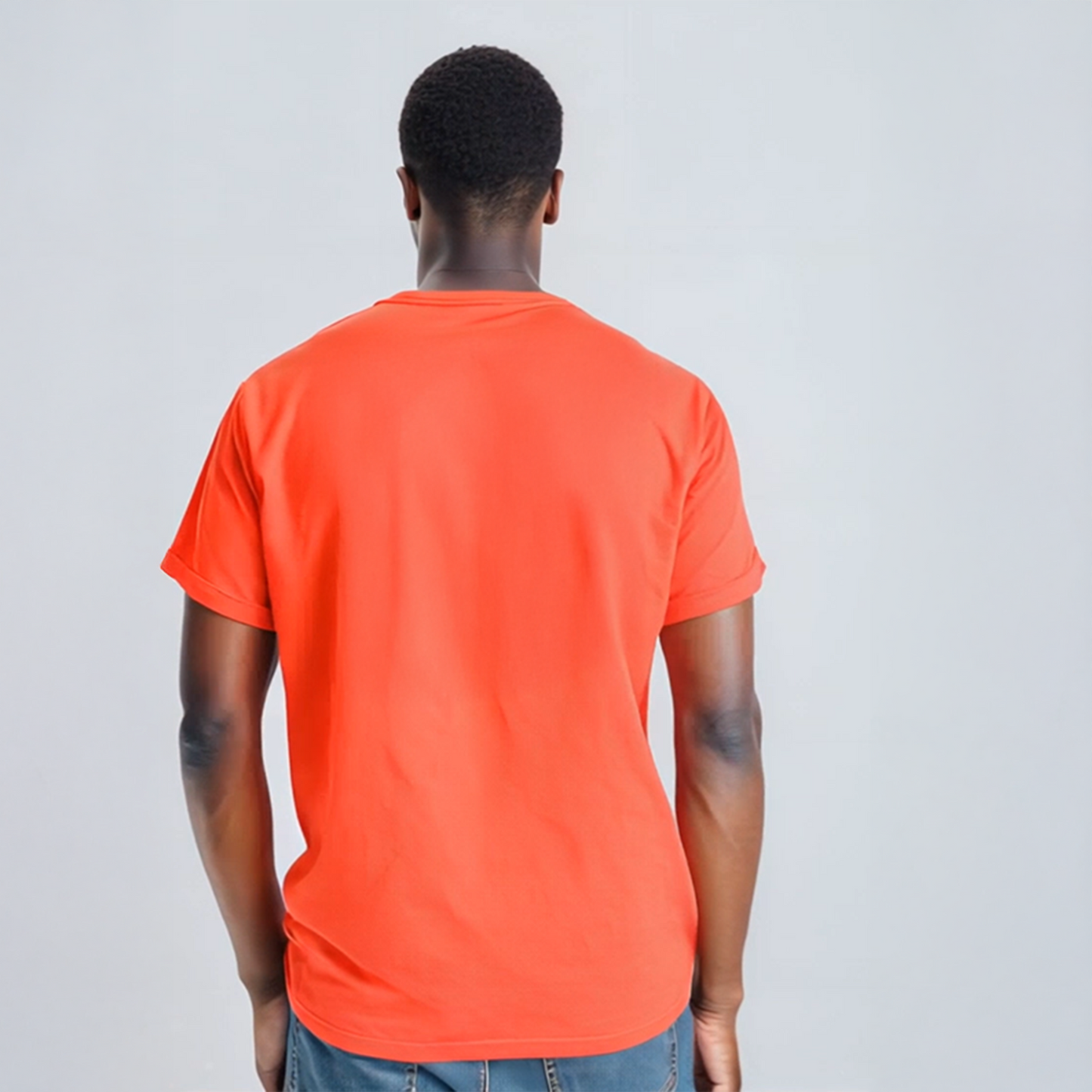 Man wearing red graphic t-shirt with bold vertical white text that reads “Wealth Is Built One Decision At A Time,” paired with jeans