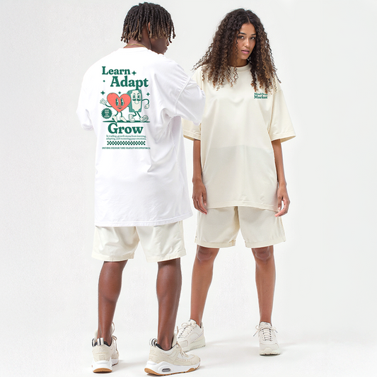 Two models wearing Bull & Bear cream oversized sets; back of shirt reads “Learn. Adapt. Grow.” with heart and brain graphic, front says “Mind Over Market”
